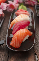 Sushi nigiri set on a black plate over wooden table