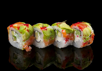 Japanese cuisine. Sushi roll with salmon avocado and tobiko over black background.