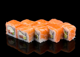 Japanese cuisine. Salmon sushi roll over black background.