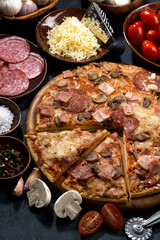 pizza with salami and ingredients on a black background