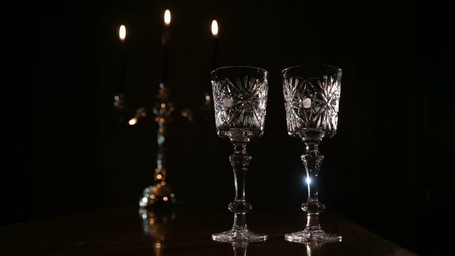 Two glasses and candle light at the restaurant.Two wine glasses,burning candles in a chandelier.Romantic atmosphere with wine glasses and candles.