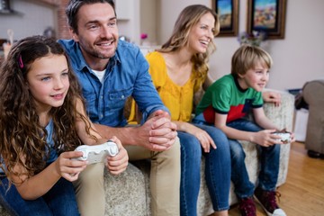 Family sitting on sofa and playing video game