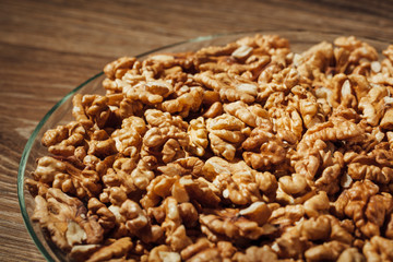 shelled walnuts on a plate, wooden background