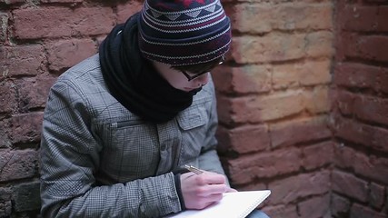 Lonely teenage boy writing down sad memories, emotions and feelings in diary