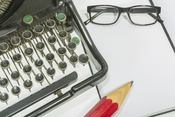 antique typewriter with blank book and reading glasses