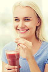 smiling woman drinking juice or shake at home