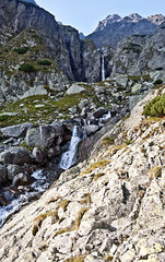 series of waterfalls and cascades with peaks on the background in Velka Zmrzla dolina valley in High Tatras mountains