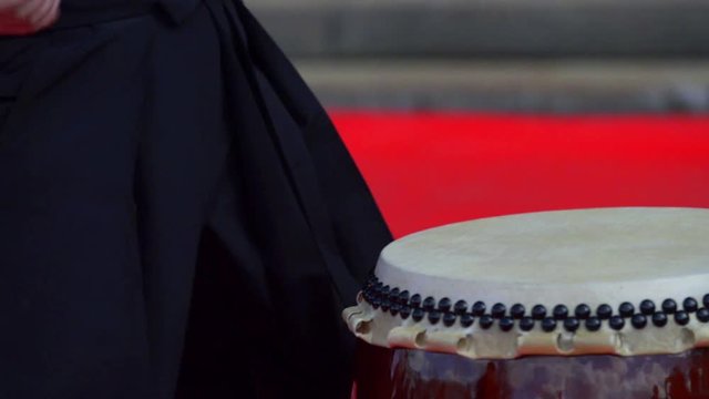 Japanese artist is drumming on traditional taiko drums. Drumsticks beating on a traditional drum