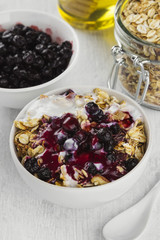 Breakfast: granola, yogurt, honey, blueberry on a white backgrou