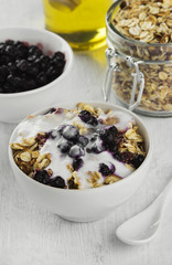 Breakfast: granola, yogurt, honey, blueberry on a white backgrou