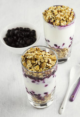 Useful dessert of granola, yogurt and blueberry in glass on a wh
