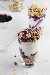 Useful dessert of granola, yogurt and blueberry in glass on a wh