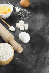 Ingredients for pastries: flour, eggs, milk against a dark backg