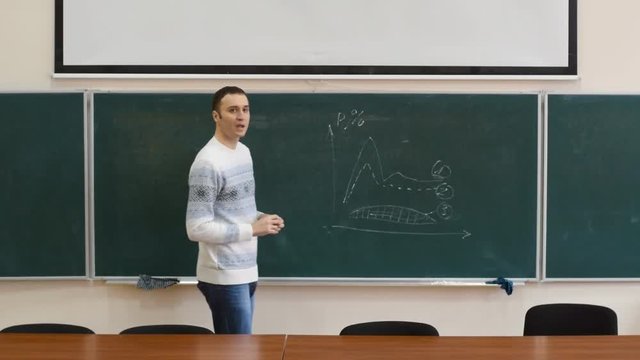 Young white reporter goes to the board. He argues patterns depicted on the chart. He appends the notation on the chart with chalk.