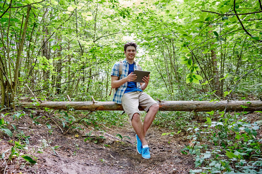 happy man with backpack and tablet pc in woods