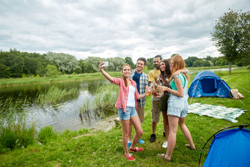 Fototapeta premium happy friends taking selfie by smartphone at camp
