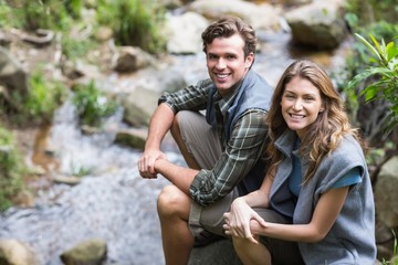 Portrait of hikers sitting on rock by stream