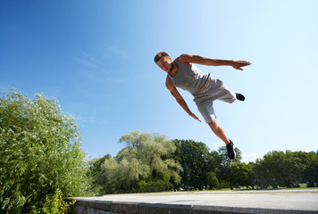 sporty young man jumping in summer park