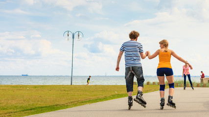 Fototapeta premium Young couple on roller skates riding outdoors