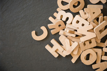 Many wooden letters on black background. Copy space.