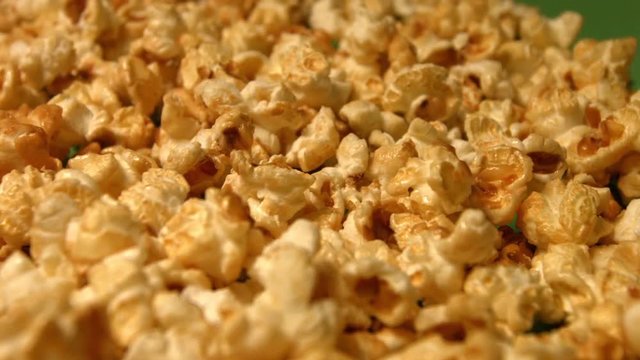 Popcorn on a green background. Slow motion. Close-up. Horizontal and vertical pan. 3 Shots