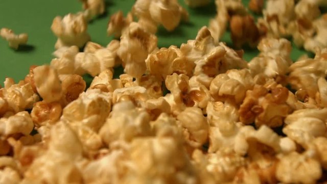 Popcorn on a green background. Slow motion. Close-up. Horizontal pan. 2 Shots
