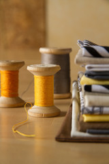 Modern patchwork fabrics in black, brown, white, yellow and grey on the wood table with yellow sewing spools