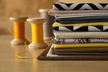 Modern patchwork fabrics in black, brown, white, yellow and grey on the wood table with yellow...