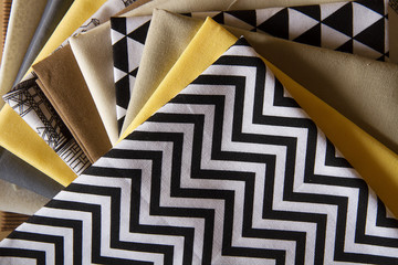 Modern patchwork fabrics in black, brown, white, yellow and grey on the wood table