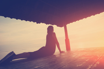 Silhouette of woman in yoga position, sun shelter near ocean. Intentional sun glare and vintage...