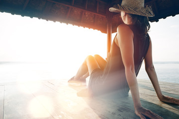 Young pretty woman resting near ocean. Blurred effect, lens flares effect, intentional sun glare