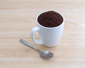 Kona coffee ground beans in a cup with spoon