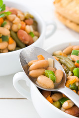 White beans with vegetables on white wooden table
