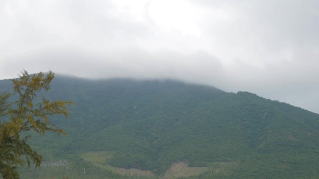 Gray cloud covering the top of the woody mountain