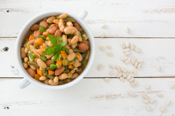 White beans with vegetables on white wooden table
