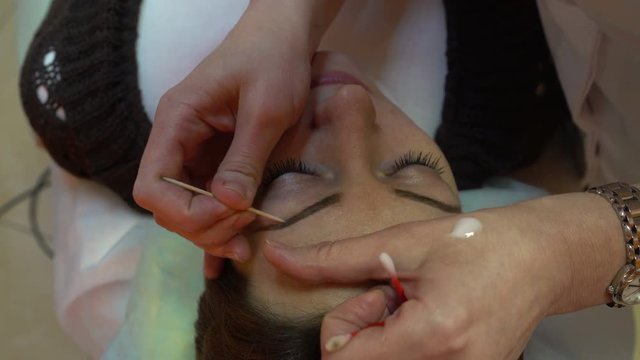 Makeup artist corrects woman's eyebrows