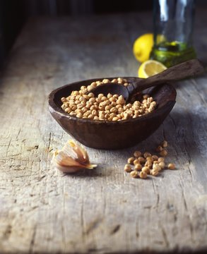 Vintage bowl and wooden spoon with raw chick peas and garlic cloves