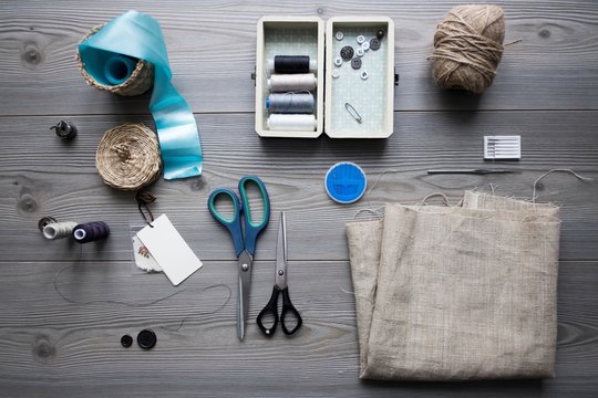 Overhead view of sewing equipment with textiles, threads and scissors