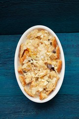 Baked panettone pudding in oval baking dish on navy blue backgro