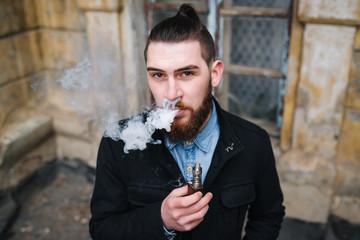 Man with  beard smoking electronic cigarette outdoor