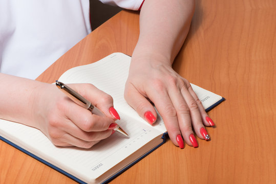 Female hands with manicure over pages of a notebook