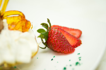 Very elegant presentation of creamy dessert with crunchy sugar decor and strawberry lying in front