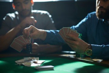 Man gambling car key playing card game at pub card table