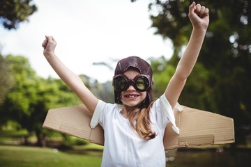 Happy girl standing in park with hands raised