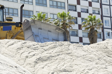  excavator  on the city  beach working moving the sand