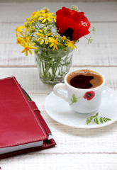A cup of coffee and a bouquet of flowers, a notebook