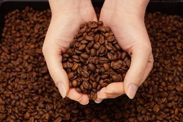 Woman hands and freshly roasted coffee beans