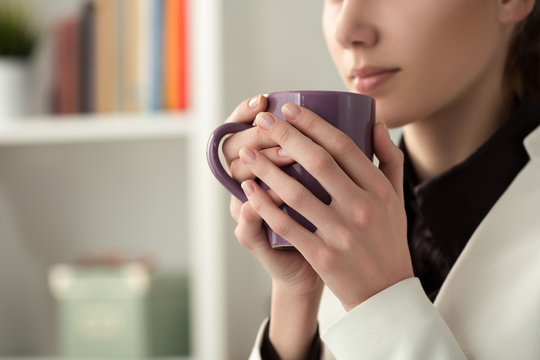 Close up of young beautiful woman hands holding hot cup of coffe