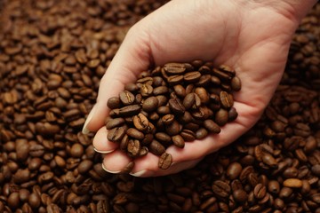 Woman hand and freshly roasted coffee beans