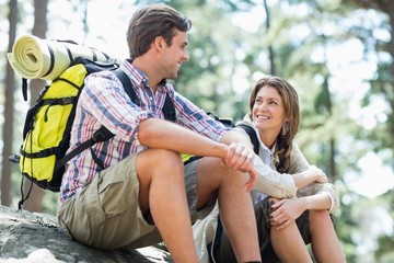 Couple looking face to face while sitting on rock 